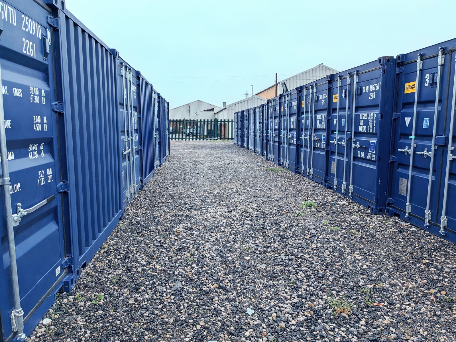 A row of navy blue JB Storage Solutions containers on the gravel yard in Brighouse